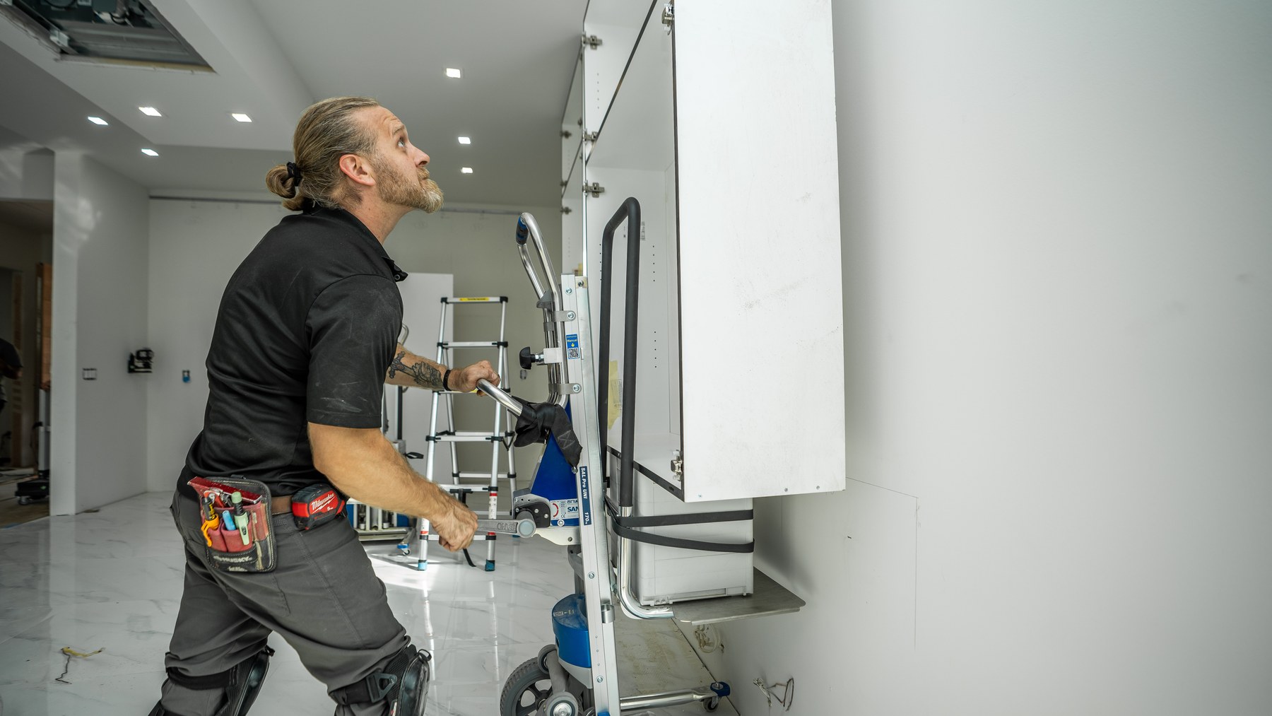 Installer raising an upper cabinet into place with the LiftKar Cabinet Pro