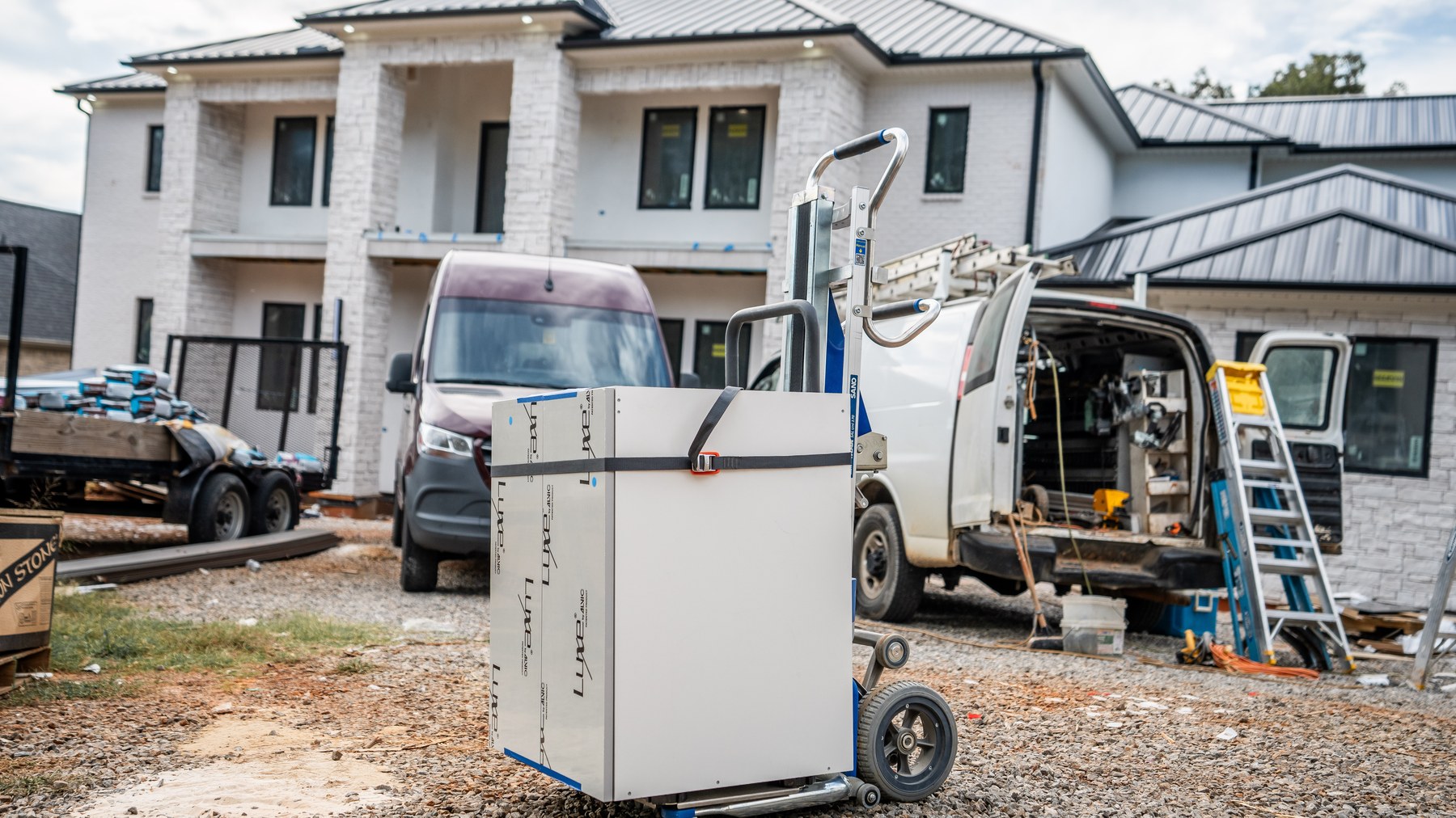 LiftKar Cabinet Pro carrying a strapped cabinet across a gravel jobsite
